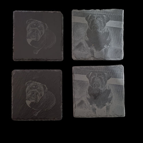 Four engraved stone coasters with dog illustrations on a white background.